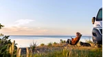 Kvinna vid husbil vid havet