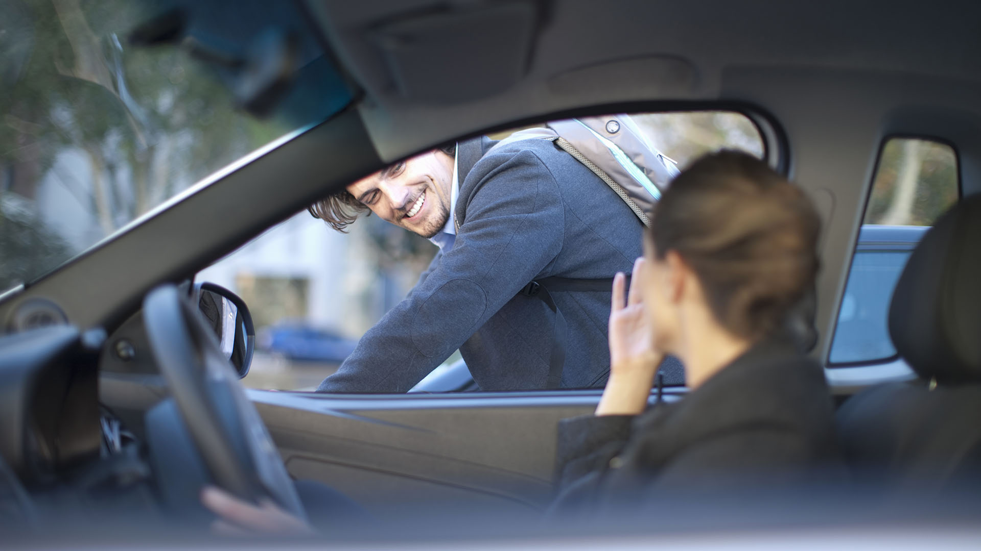 Kvinna kör eldriven företagsbil förbi cyklist på stadsgata
