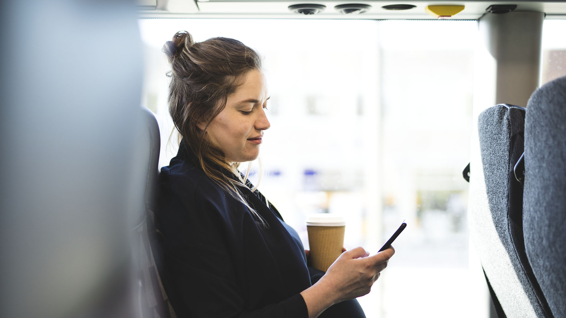 Kvinna med mobil på buss